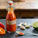 homemade extra spicy hot sauce in a glass bottle with roasted peppers and garlic