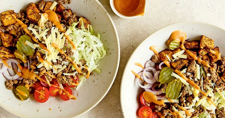 Burger bowl with seasoned ground beef, lettuce, pickles, tomatoes, cheddar, and special burger sauce