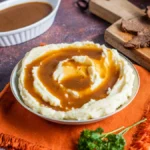 au jus sauce served with mashed potatoes and sliced roast beef on a cutting board
