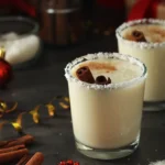 two glasses of coquito with shredded coconut rim and cinnamon garnish on a festive table
