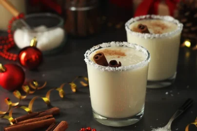 two glasses of coquito with shredded coconut rim and cinnamon garnish on a festive table