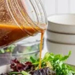 balsamic vinaigrette being poured from a mason jar over a green salad