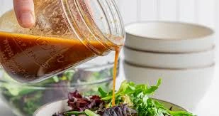 balsamic vinaigrette being poured from a mason jar over a green salad