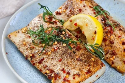 pan seared mahi mahi fillets with lemon wedge, herbs, black pepper, and red pepper flakes
