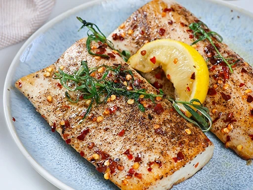 pan seared mahi mahi fillets with lemon wedge, herbs, black pepper, and red pepper flakes