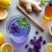 purple wellness drink in a glass with mint, surrounded by lemon, ginger, cinnamon stick, honey, and cucumber slices