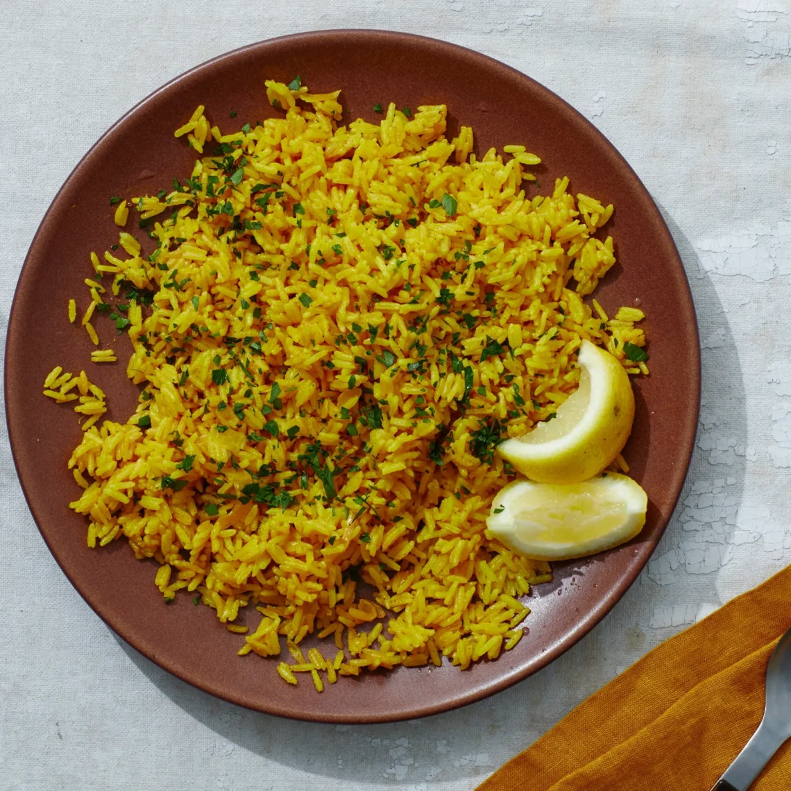 fluffy yellow rice in a bowl garnished with herbs, served as a golden side dish
