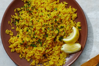 fluffy yellow rice in a bowl garnished with herbs, served as a golden side dish