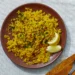 fluffy yellow rice in a bowl garnished with herbs, served as a golden side dish