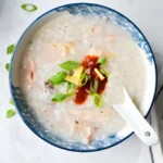 creamy rice porridge in a bowl with ginger, green onions, and optional egg topping