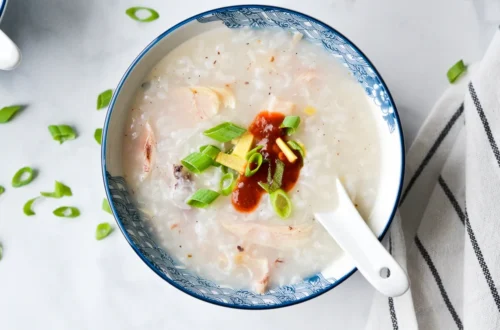 creamy rice porridge in a bowl with ginger, green onions, and optional egg topping