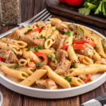 creamy rasta pasta with penne, chicken pieces, bell peppers, herbs and red pepper flakes
