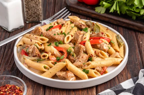 creamy rasta pasta with penne, chicken pieces, bell peppers, herbs and red pepper flakes