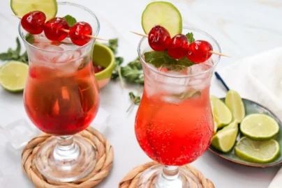 two Shirley Temple mocktails with ice, grenadine, cherry skewers and lime slices