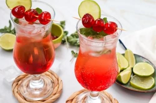 two Shirley Temple mocktails with ice, grenadine, cherry skewers and lime slices