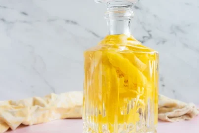 homemade limoncello in a glass bottle with lemon zest strips infusing inside