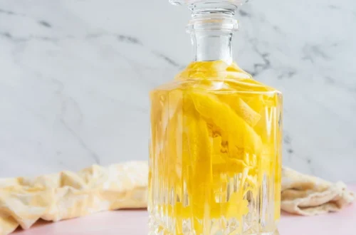 homemade limoncello in a glass bottle with lemon zest strips infusing inside