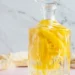 homemade limoncello in a glass bottle with lemon zest strips infusing inside