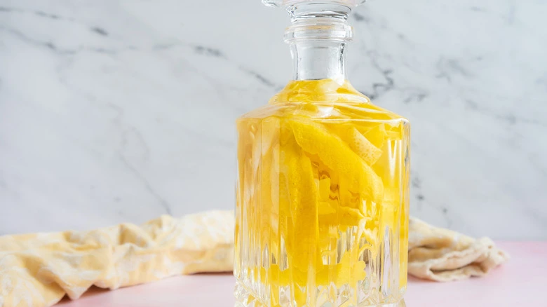 homemade limoncello in a glass bottle with lemon zest strips infusing inside