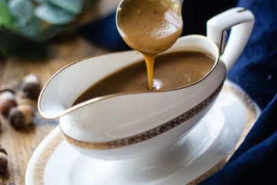 brown gravy being poured from a ladle into a white gravy boat