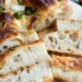 sliced sourdough focaccia bread showing airy holes and golden crust on a wooden board