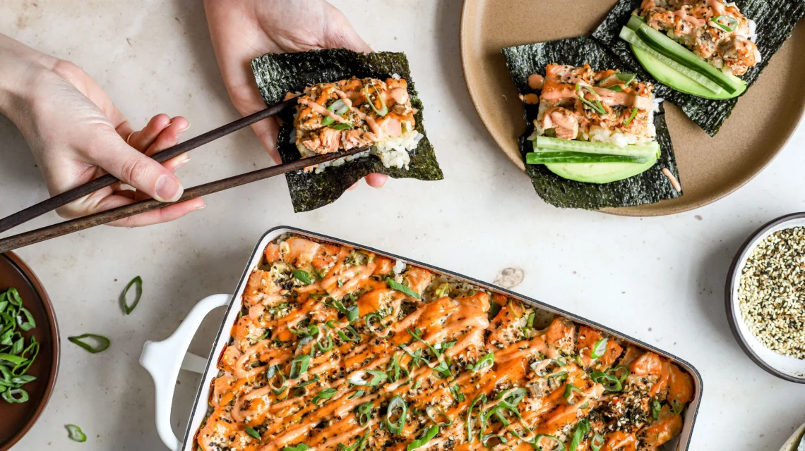 sushi bake casserole with spicy mayo drizzle served with nori sheets, cucumber and green onion